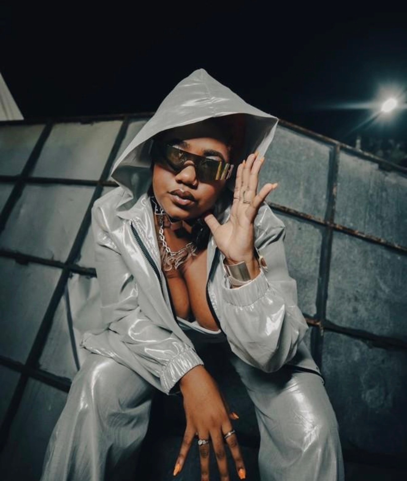 Artist in a reflective silver hooded outfit and sunglasses