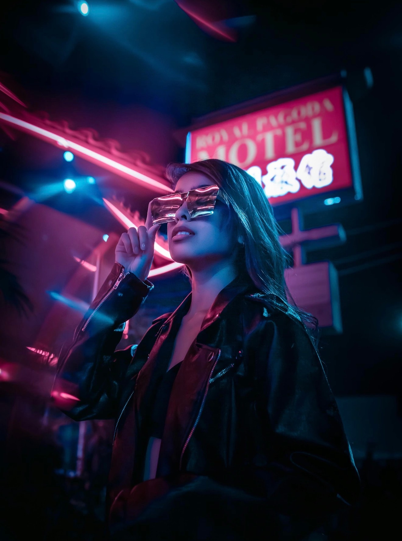 Artist in reflective sunglasses beneath neon lights