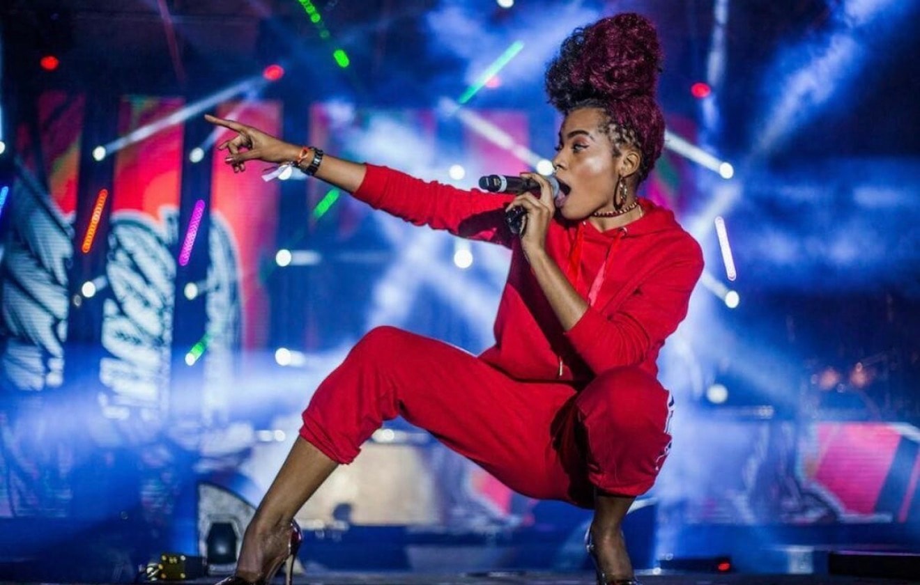Artist in red performing onstage under colorful concert lights